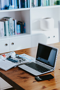 Silver laptop with various items on a table thumbnail