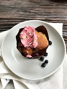 cupcake with pink frosting on white ceramic plate thumbnail