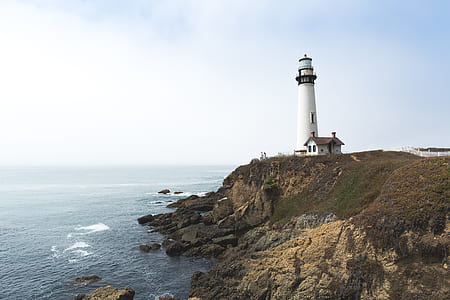 white lighthouse near cliff and ocean during daytime thumbnail