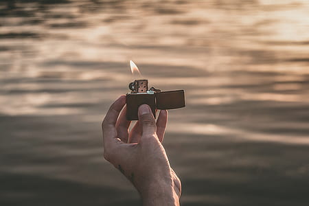 person holding lighted black flip lighter thumbnail