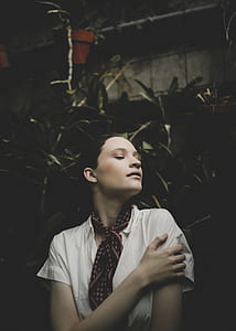 woman in white button-up shirt holding her arm thumbnail