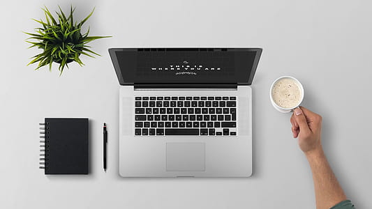 MacBook Pro beside cup with book and pen thumbnail