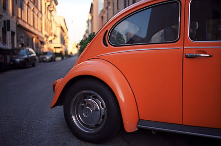 orange Volkswagen Beetle coupe parked diagonally on side of road at daytime thumbnail