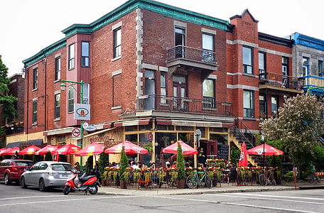 brown building besides red patio umbrellas thumbnail