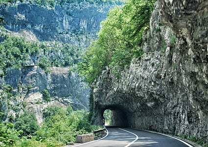 gray road besides rock formation at daytime thumbnail