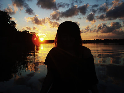 silhouette of woman sitting on beach while looking at the sunset thumbnail