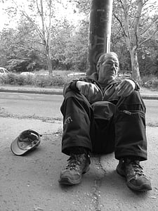 man sitting beside a pole thumbnail