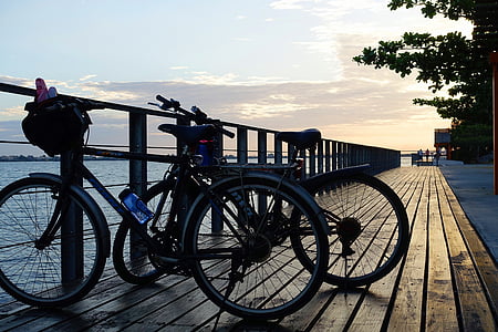 two black bike parked near body of water during golden hour thumbnail