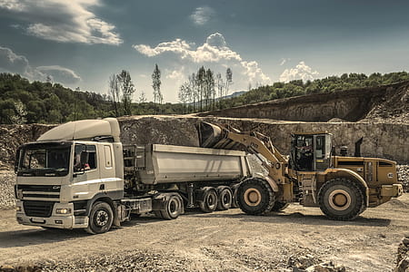 Front Load Loader Beside White Dump Truck thumbnail