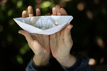 selective focus photography of person holding paper boat thumbnail
