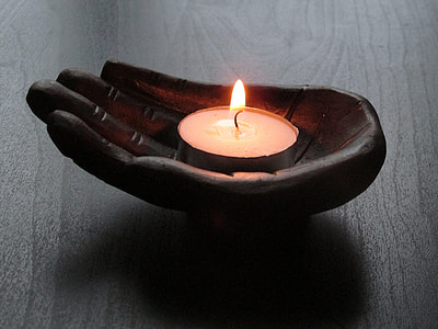 black wood carve hand candle holder with white candle on top of brown surface thumbnail