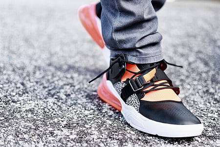selectiv focus photography of person wearing sneakers on gray road thumbnail