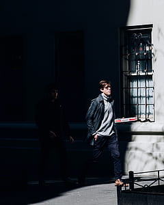 two men walks beside gray concrete building during daytime thumbnail