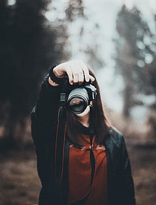woman in red top holding DSLR camera thumbnail