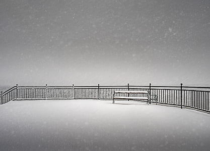 snow covered black metal bench near black rails thumbnail