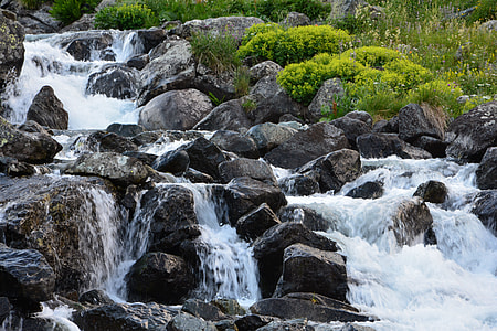 river flowing through rocks surrounded by green grass thumbnail