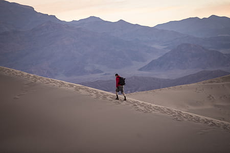 man walking desert near mountain range thumbnail