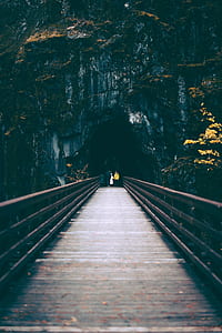 people walking on wooden bridge towards cave thumbnail