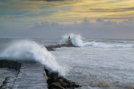 red and white wave of water hitting lighthouse during daytime thumbnail