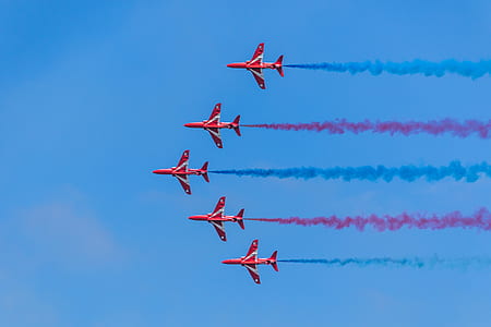 five red jets leaving blue and red contrails on blue sky thumbnail