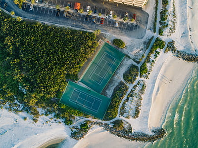 aerial photography of two tennis courts near body of water and parking lot thumbnail