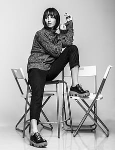 grayscale photo of woman sitting on chairs thumbnail