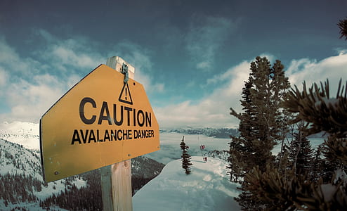 yellow and black Caution signage on snow-cover mountain thumbnail