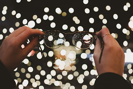 person holding eyeglasses in front of boke lights thumbnail
