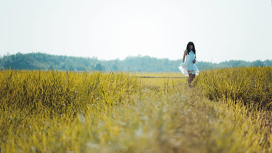 Depth of Field Photography of Woman Wearing White Sleeveless Dress Standing on Green Grass Field thumbnail