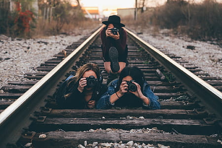 three women taking photo on train rail thumbnail