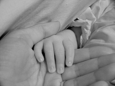 gray scale photography baby holding person's hand thumbnail