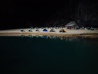 photo of a body of water near on the sand with dome tents thumbnail