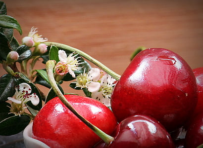 close up photo of red cherry beside white petaled flowers thumbnail