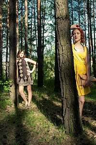 two women standing beside tree thumbnail