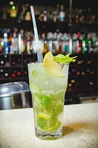clear drinking glass with sliced lemon and straw on brown surface thumbnail