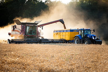 yellow and blue crop harvester near trees at daytime thumbnail
