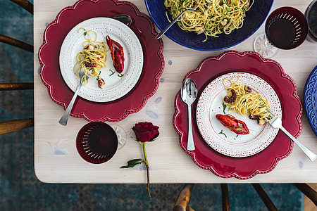 Fancy dinner with seafood pasta, crayfish and red wine by the table decorated with roses thumbnail