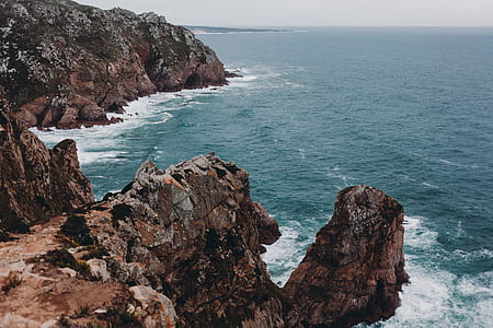 landscape photography of brown rocky mountains beside seashore thumbnail