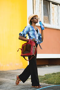 Woman in Blue Top Holding Blue Bottle and Red 2-way Bag Outdoors thumbnail