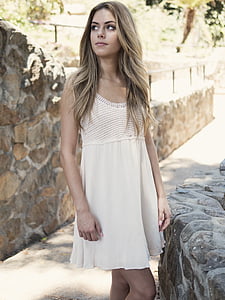 woman in white scoop-neck sleeveless dress standing near wall thumbnail