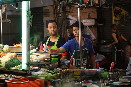 men standing behind food stall while serving foods thumbnail