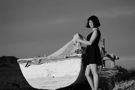 grayscale photo of woman beside boat thumbnail