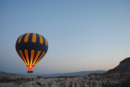 blue and yellow hot air balloon hovering above mountain thumbnail