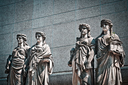 four white statues standing near gray wall thumbnail