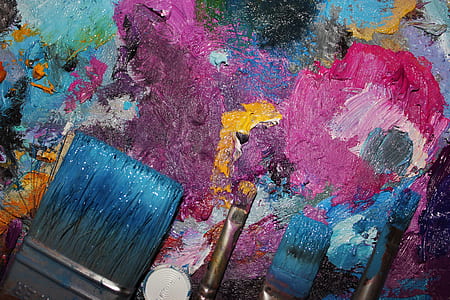 four paintbrushes on top of pink, blue, and pink abstract painting thumbnail