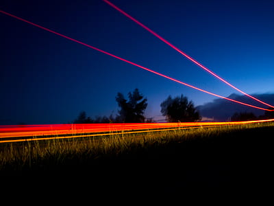 time lapse photography of vehicle travelling on road near grass field during nighttime thumbnail