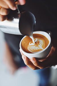 person pouring milk on cafe latte thumbnail