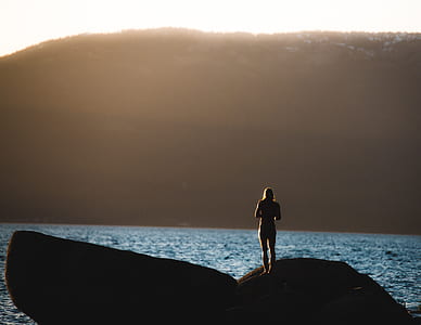 woman standing on rock in front of sea across mountain during daytime thumbnail