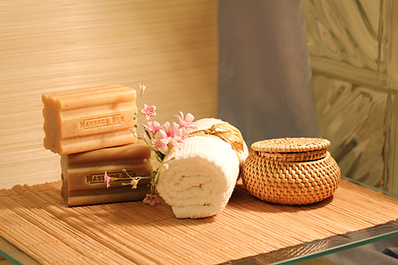 two soap bars near white face towel and brown basket on brown wooden table thumbnail