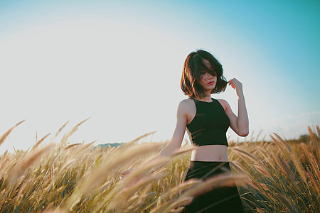 woman touching her hair while standing on grass field thumbnail